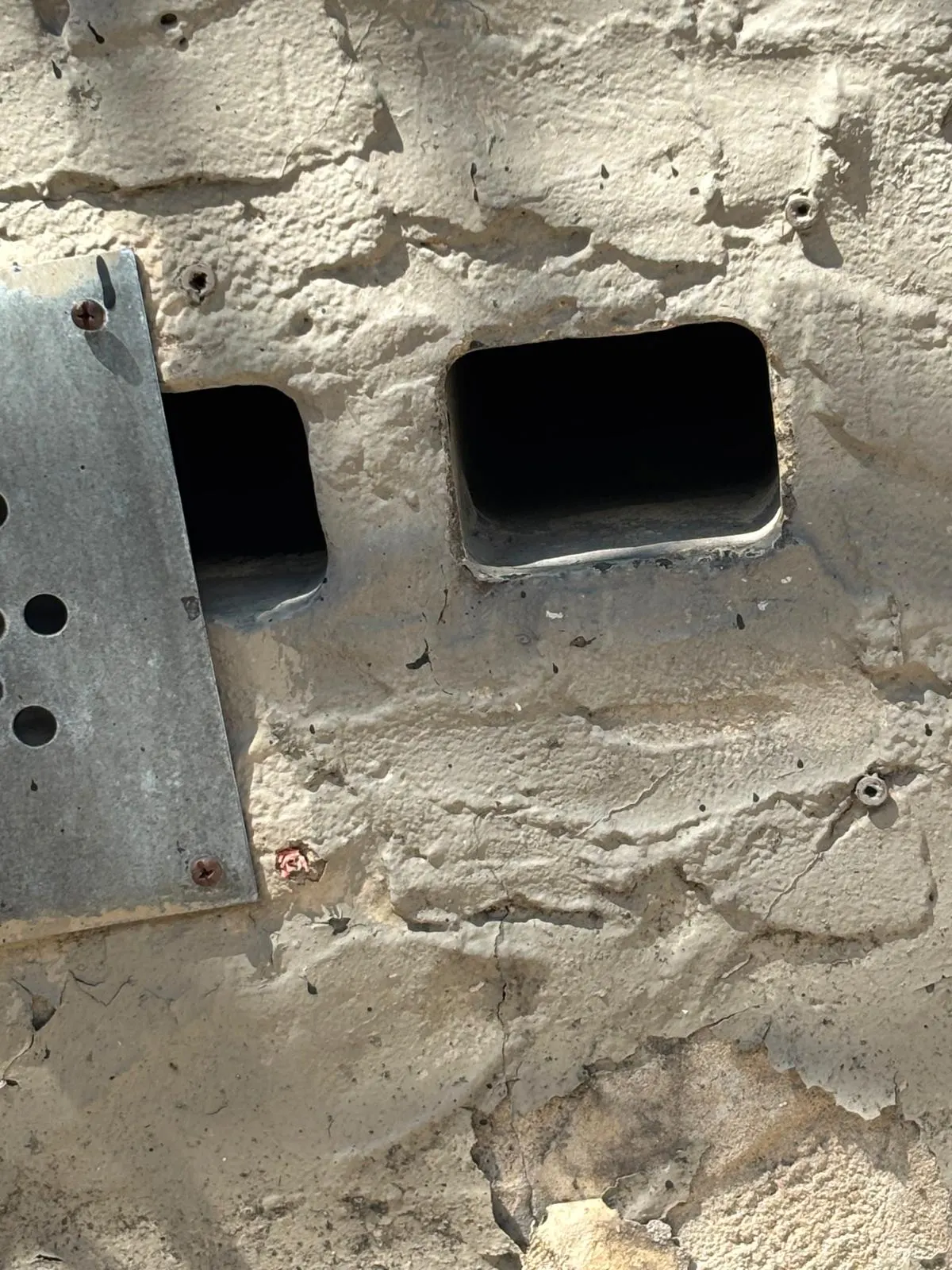 Two open rectangular holes cut into a concrete foundation wall