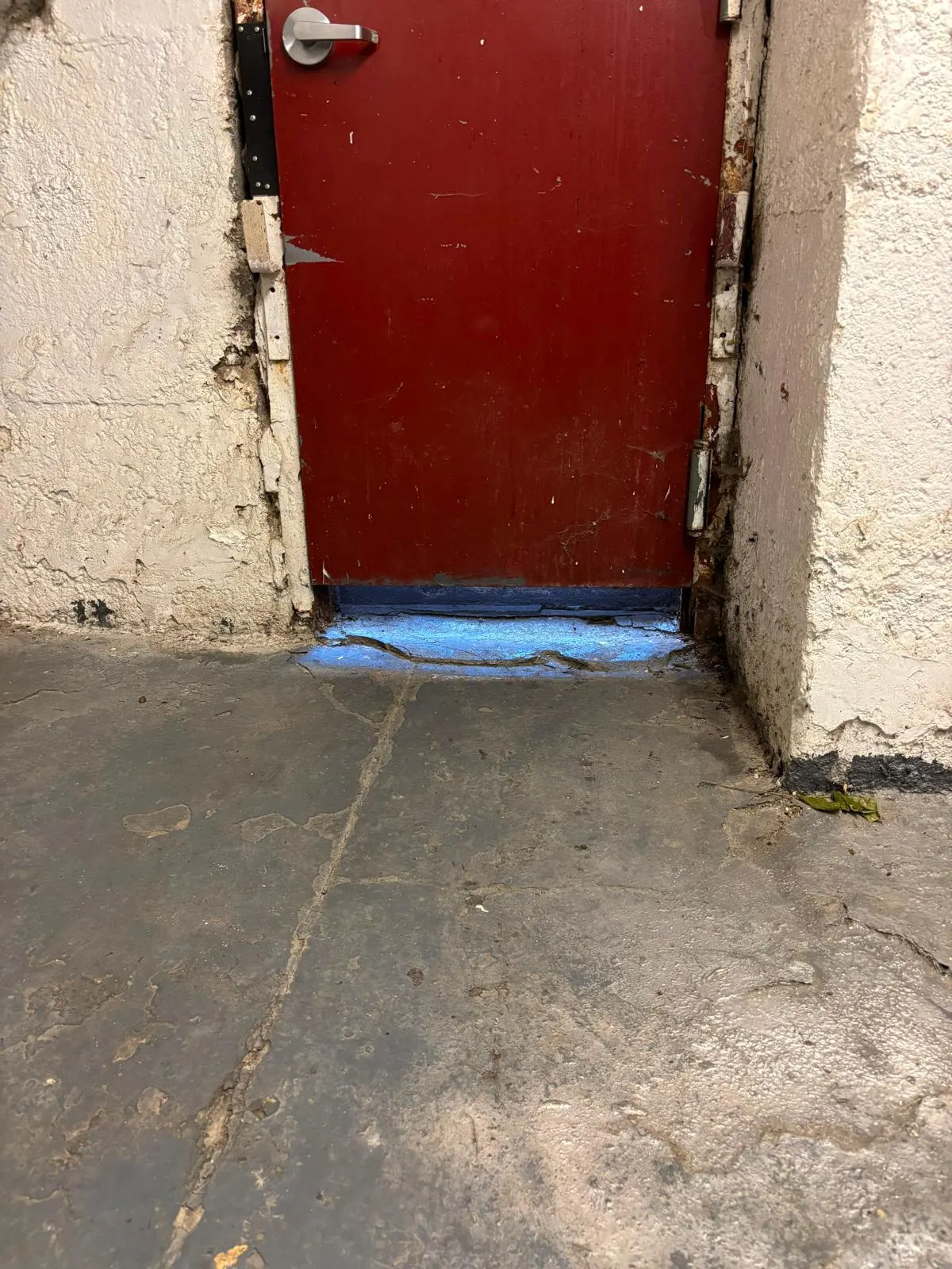 Daylight visible beneath a closed steel service door
