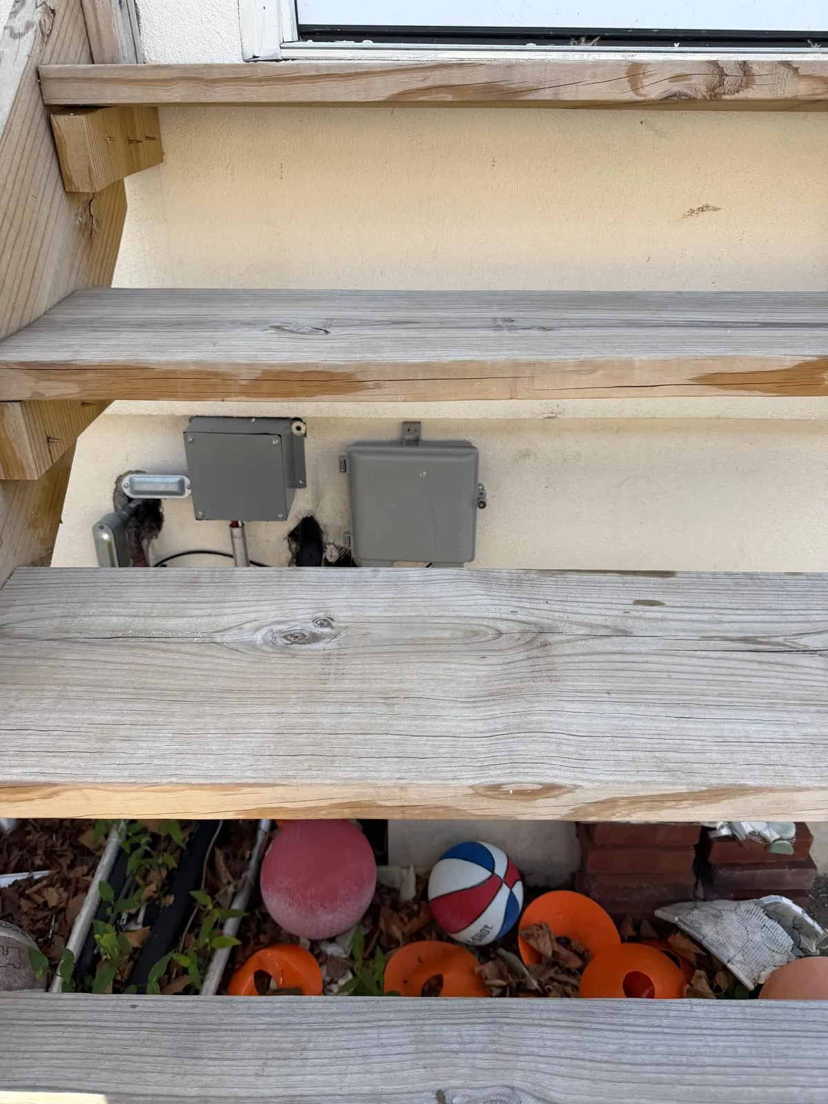 Open service penetrations in a wall beneath wooden deck steps
