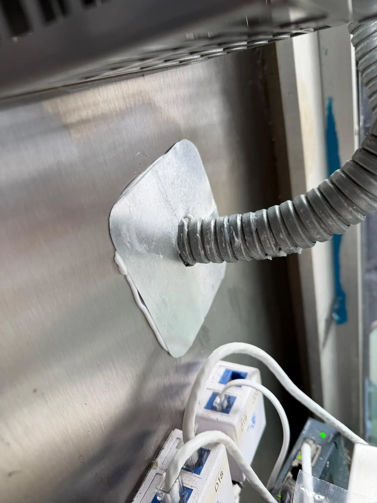 The same conduit with a steel plate and sealant closing the gap