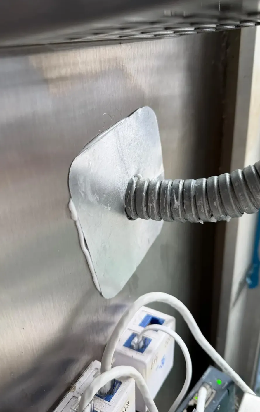 The same conduit with a steel plate and sealant closing the opening