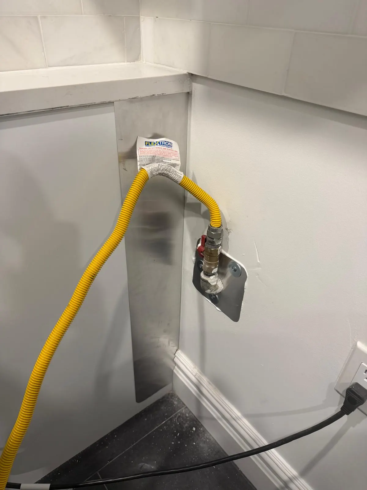 A new gas line entering a wall through a steel plate sealed around the pipe