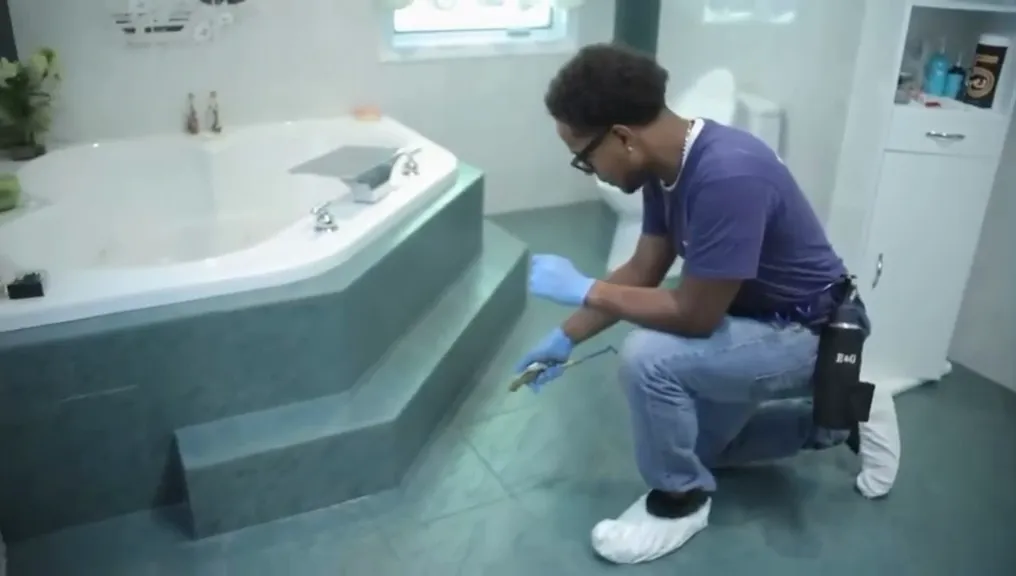 A technician treating along the base of a bathtub surround