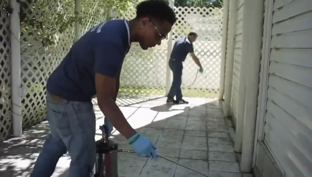 A technician treating the exterior perimeter of a building
